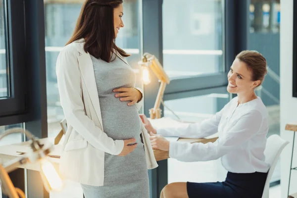 かなり妊娠中の女性彼女の同僚に転換し、笑みを浮かべて — ストック写真