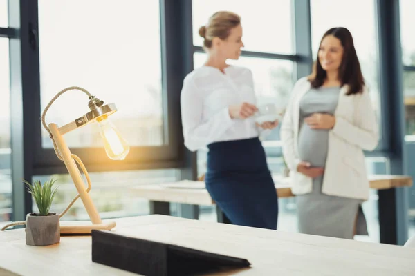 Heldere lamp staande op de tafel terwijl jonge vrouwen praten — Stockfoto