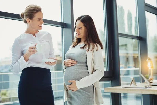 Pregnant employee talking to her employer and smiling — Stock Photo, Image