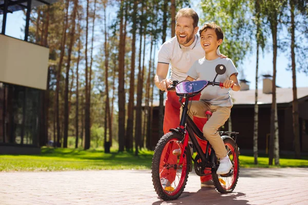 Cuidar a papá enseñando a su hijo a montar en bicicleta — Foto de Stock