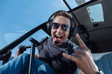 Overjoyed helicopter pilot showing sing of horns clipart