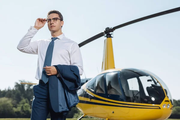 Angenehme junge Führungskraft justiert Brille beim Heliport-Besuch — Stockfoto