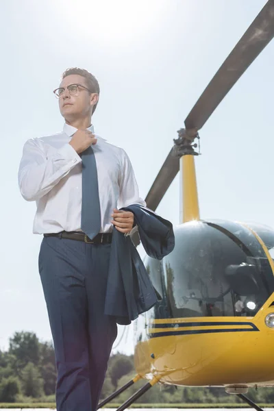 Knappe jonge zakenman poseren in de buurt van een helikopter — Stockfoto