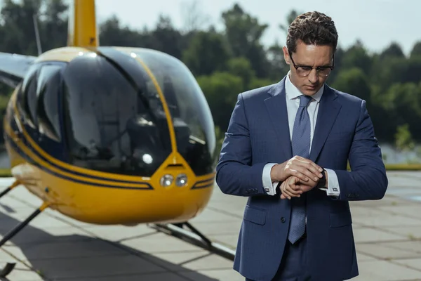 Angenehmer junger Ceo überprüft Zeit vor Hubschrauberflug — Stockfoto