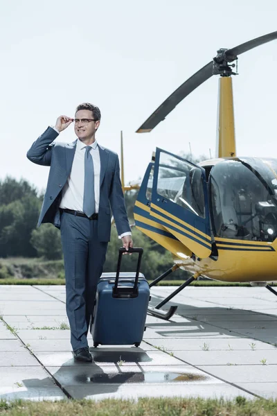 Charming young executive leaving helipad and carrying suitcase — Stock Photo, Image