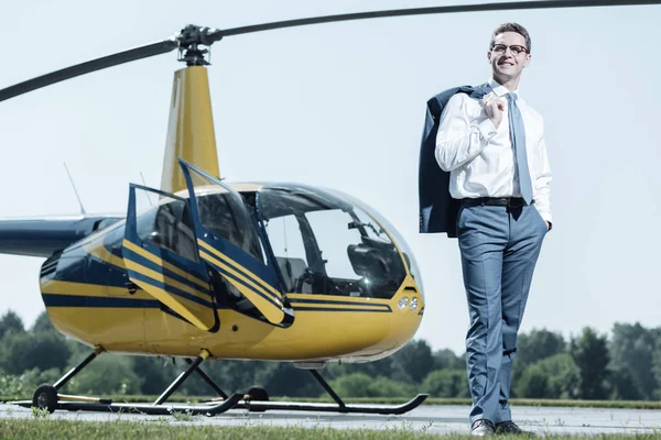 Upbeat young owner standing near helicopter — Stock Photo, Image