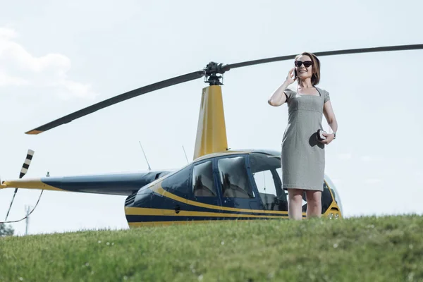 Vrolijke zakenvrouw praten aan de telefoon tijdens helikopterplatform inspectie — Stockfoto