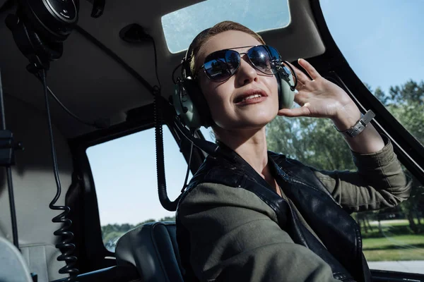重要な指示に従います 美しい若い女性パイロットで座ってヘリコプター ブースと空気のトラフィック コント ローラーの指示を聞いて — ストック写真