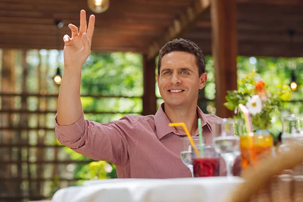 Hombre atractivo levantando la mano sentado en el restaurante —  Fotos de Stock
