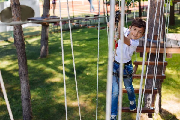 Vrolijke preteen jongen die zich voordeed tijdens het klimmen op touw park — Stockfoto