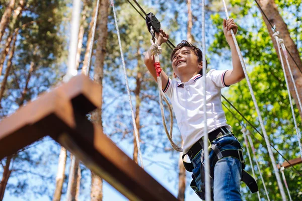 Upbeat preteen boy climbing at adventure park — Stock Photo, Image