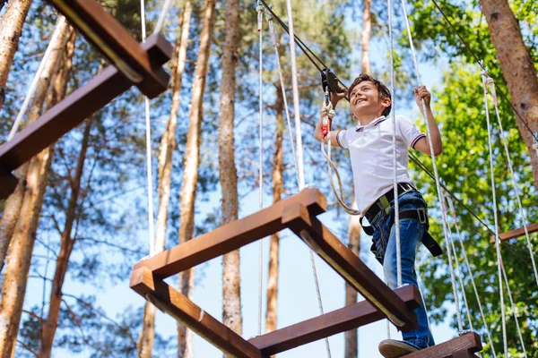 Happy preteen boy climbing bars at rope park — Stock Photo, Image