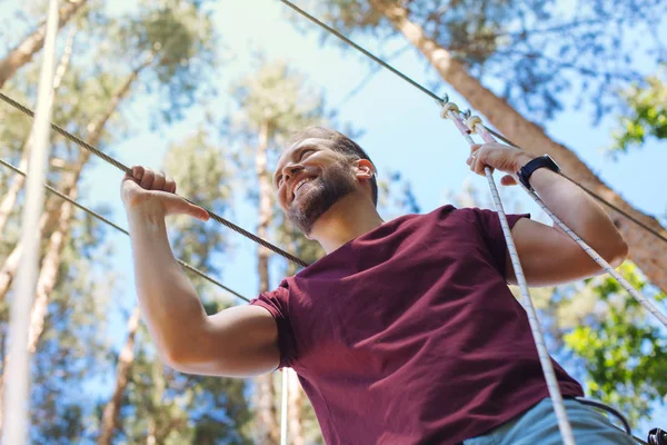 Excited young man enjoying himself at rope park — Stock Photo, Image