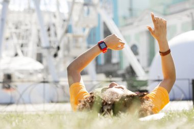 Kıvırcık saçlı Genç kadın şehir merkezinde çim üzerinde yalan