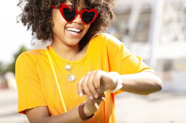 İyimser kıvırcık kadın akıllı saatini kontrol