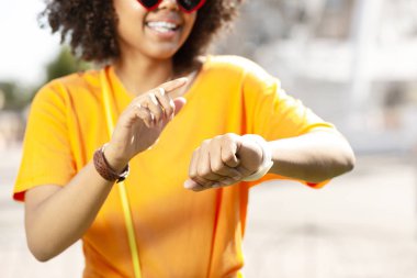 İyimser kıvırcık kadın akıllı saatinin ayarlarını kontrol