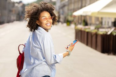 Neşeli kıvırcık kadın tahmin onun Smartphone cep telefonu ile kontrol