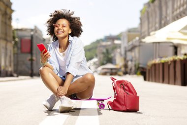 Neşeli kadın mini kaykay üzerinde otururken Internet sörf