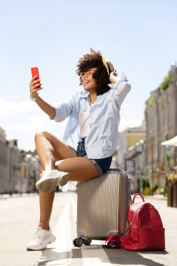 Kıvırcık genç kız bavula otururken iletileri okuma