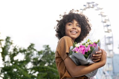 Buket çiçek onun göğsüne basarak sevimli kıvırcık kadın