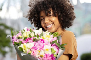 Çiçek tutan güzel bir kıvırcık kadın yakın çekim