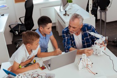 Belgili tanımlık laptop önünde oturan neşeli pozitif çocuklar