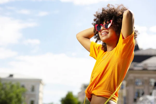 Agréable femme souriante posant les mains derrière la tête — Photo