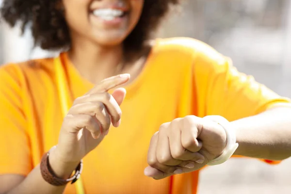 Smiling curly woman making changes of smart watch settings — Stock Photo, Image