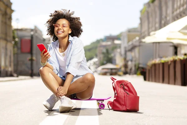 Neşeli kadın mini kaykay üzerinde otururken Internet sörf