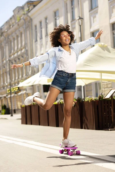 Angenehme fröhliche Mädchen, die anmutig Skateboard fahren — Stockfoto