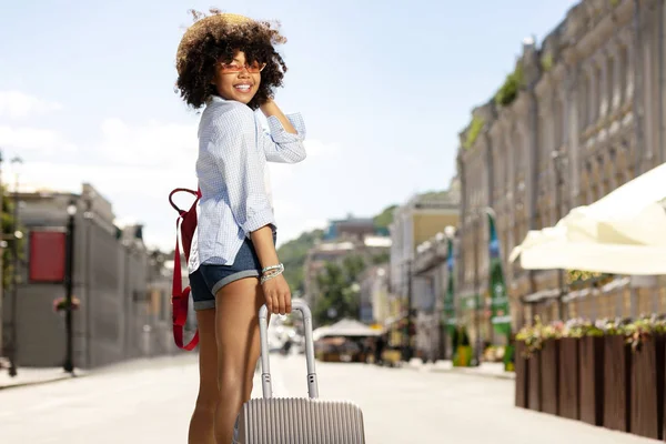 Upbeat turista femenina posando con una maleta — Foto de Stock