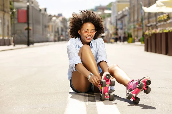 Encantadora chica rizada poniéndose patines — Foto de Stock