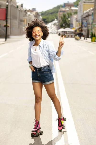 Glad flicka slående söt pose medan rullskridskor — Stockfoto