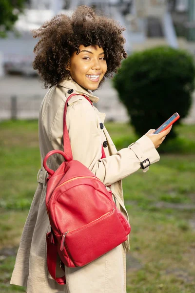 Pleasant curly woman checking weather app while walking