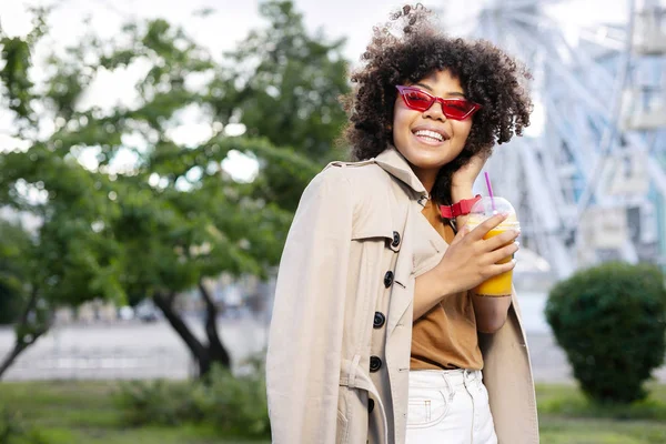 Trençkot suyu Kupası tutan hoş kıvırcık kadın