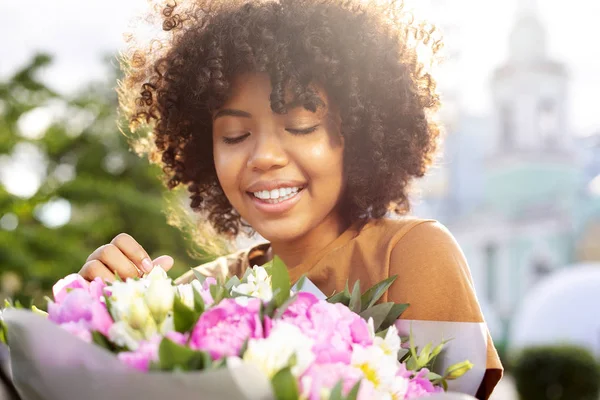 Mujer bastante rizada admirando ramo de flores —  Fotos de Stock