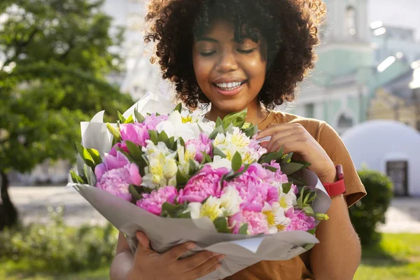 Mujer rizada feliz mirando ramo de flores —  Fotos de Stock