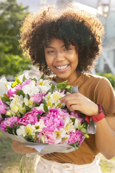 Mujer bastante rizada mostrando su ramo de flores — Foto de Stock