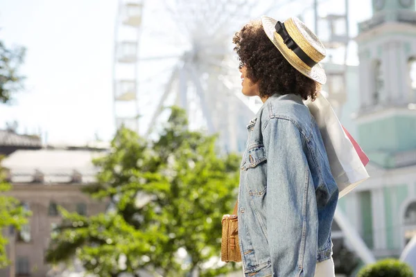 Alışveriş torbaları ile şık kıvırcık kadın yan görünüm
