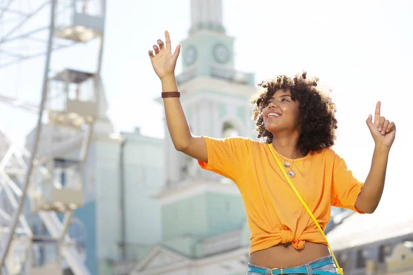 Pretty curly woman raising hands and smiling happily