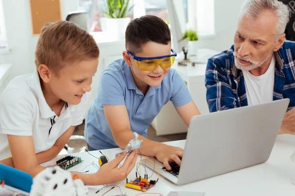 Belgili tanımlık laptop önünde oturan olumlu iyi çocuk