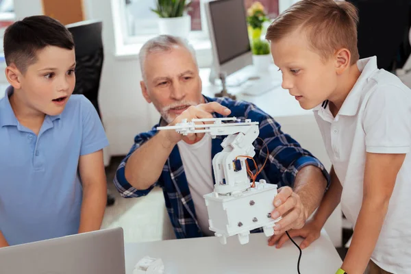 Умные любопытные мальчики смотрят на современного робота — стоковое фото