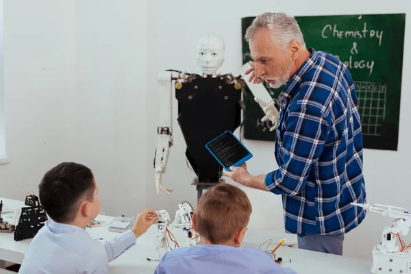 Smart professional teacher pointing at the robot — Stock Photo, Image