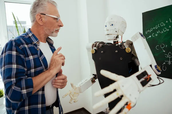 Ciddi adam robot önünde ayakta yaşlı