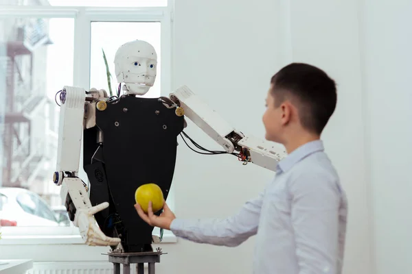 Joyful nice boy talking to the robot
