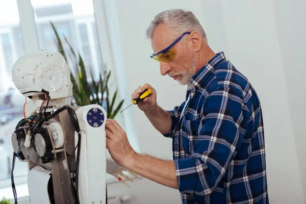 Serious elderly man standing near the robot — Stock Photo, Image