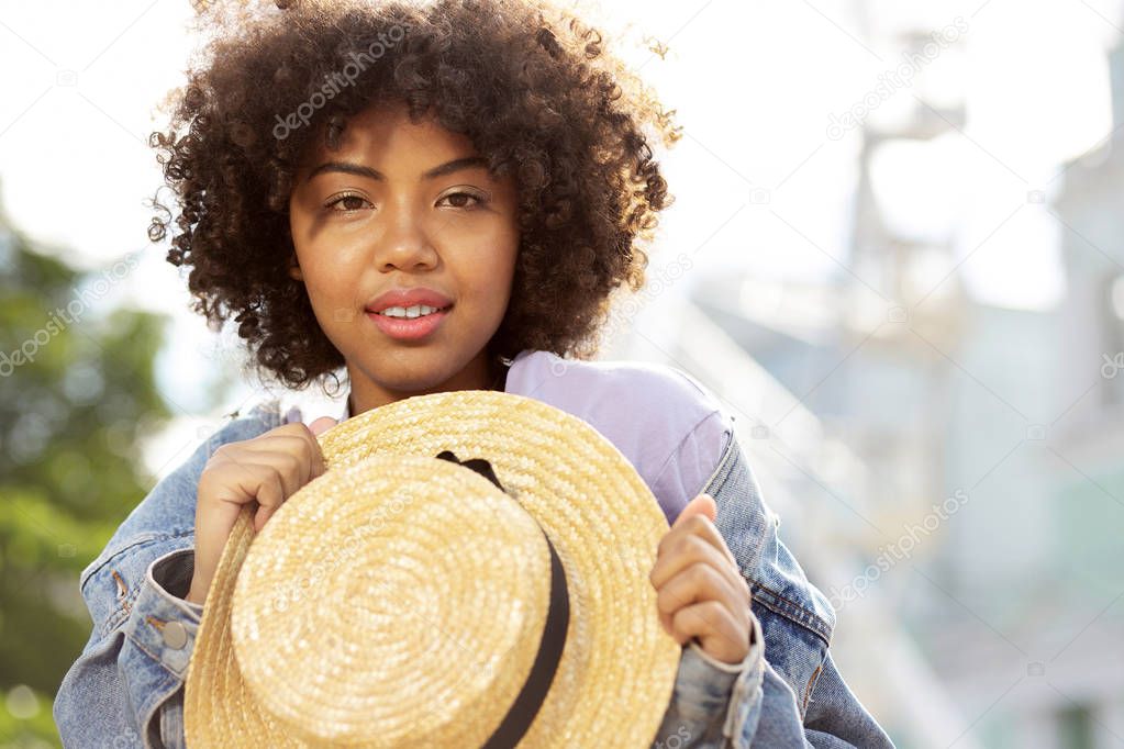 Pretty curly girl posing with a straw hat