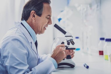 Beyaz üniforma mikroskop bakarak giyen genetiğinin