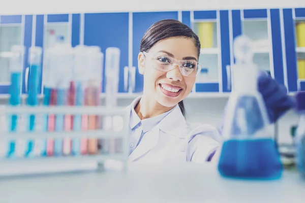 Hermoso médico sonriente de pie cerca de tubos de ensayo —  Fotos de Stock