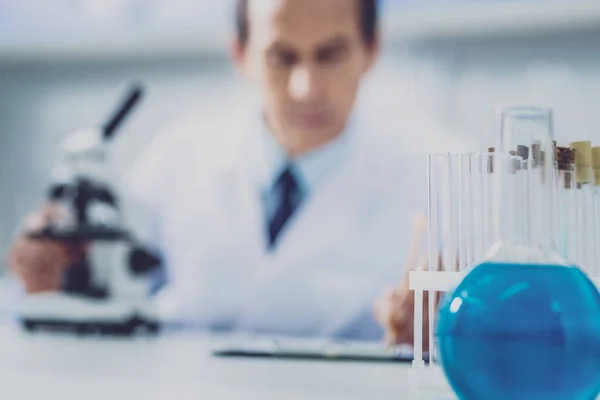 Chemist sitting at the table near bulbs with liquids Stock Photo